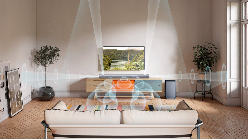 W salonie znajduje się telewizor na szafce, przed którym ustawiony jest soundbar i subwoofer. Na ekranie telewizora wyświetlany jest krajobraz z rzeką i lasem, a wokół soundbara widoczne są graficzne fale dźwiękowe.