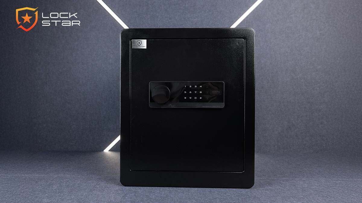 Czarny sejf z elektronicznym panelem kodowym na drzwiach. W lewym górnym rogu widoczne jest logo \'LOCK STAR\'.