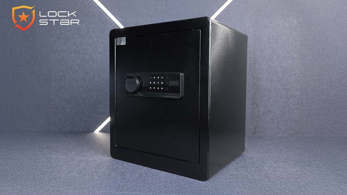 Czarny sejf elektroniczny z panelem numerycznym na drzwiach. W lewym górnym rogu widoczne jest logo \'LOCK STAR\'.