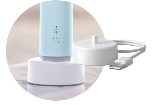 Szczoteczka umieszczona w podstawce ładującej. Obok znajduje się podstawka ładująca.