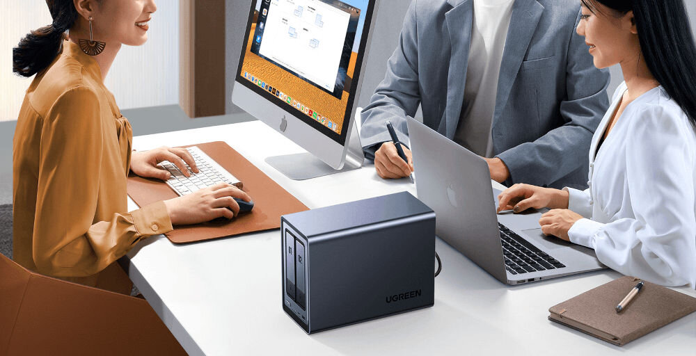 Serwer plików UGREEN NASync DXP2800 8GB RAM prezentacja serwera pomiędzy ludźmi siedzącymi w biurze przy biurku z laptopem i komputerem aluminiowa obudowa aktywny system chłodzenia trzy tryby pracy wentylatora w trybie cichym hałas nie przekracza 34 dB