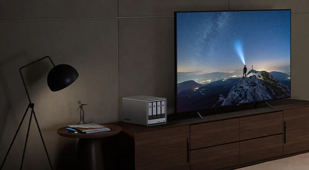 Serwer plików UGREEN NASync DXP4800 Plus 8GB RAM prezentacja urządzenia na regale w pokoju obok telewizor i lampka obsługa maszyn wirtualnych i Dockerów, uruchamia aplikacje monitoringu i serwery, z lokalnym przechowywaniem danych oraz zabezpieczeniem i szyfrowaniem