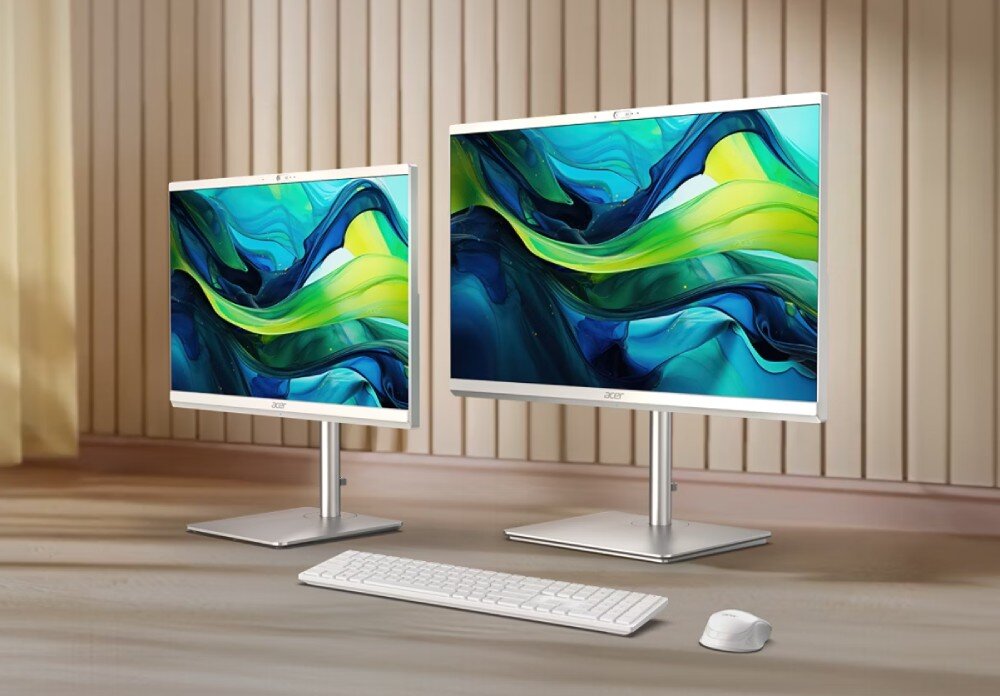 Komputer ACER Aspire C27-195ES Dwa komputery typu all-in-one z cienkimi ramkami ustawione na drewnianym blacie, jeden z mniejszym ekranem, drugi z większym, obok klawiatura i myszka, opis