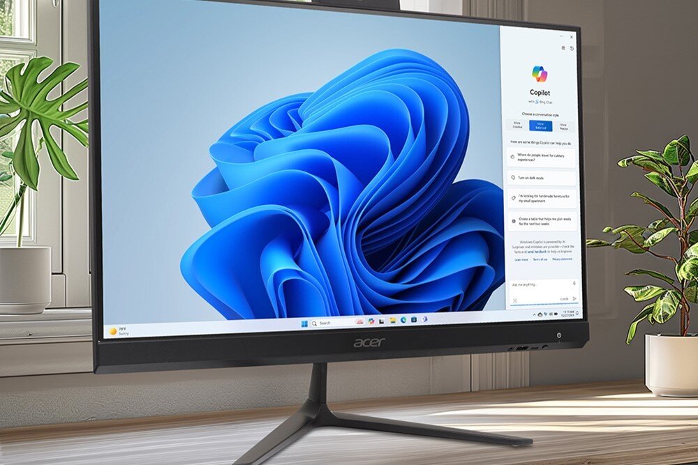 Komputer ACER Aspire C27-2E13U Komputer typu all-in-one stojący na drewnianym blacie przy oknie, z włączonym systemem operacyjnym i roślinami w tle, procesor, rdzenie, taktowanie, pamięć, karta graficzna