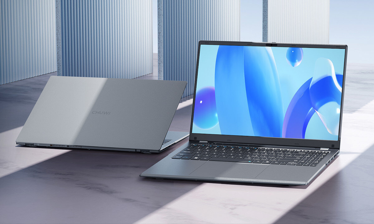 Dwa laptopy CHUWI w kolorze srebrnym na tle minimalistycznego wnętrza; jeden otwarty, prezentujący ekran z niebieską, abstrakcyjną tapetą, drugi zamknięty z widocznym logo marki na pokrywie, podkreślające elegancki design urządzenia.