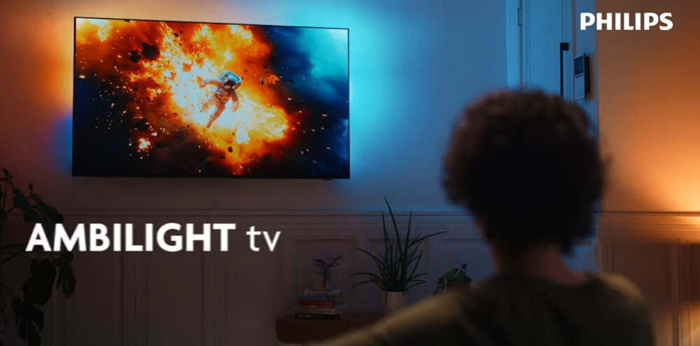 PHILIPS 55MLED920 Ambilight podświetlenie LED reagujące na obraz, telewizor zawieszony na ścianie w pomieszczeniu, osoba oglądająca tv