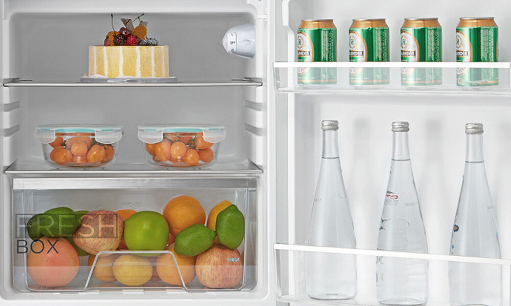 LODÓWKA MIDEA MDRD168FGE01 Zbliżenie na wnętrze lodówki z owocami, warzywami, napojami i ciastem na półkach szuflada na warzywa regulowane półki organizacja wnętrza