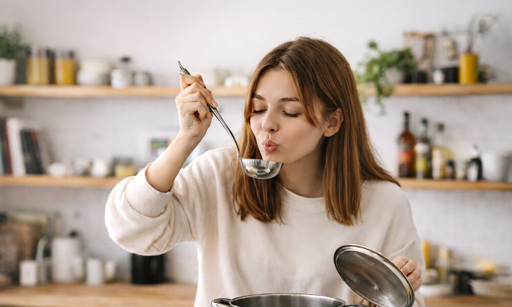 LODÓWKA MIDEA MDRD142FGE50 Na zdjęciu widać osobę stojącą w kuchni i próbującą potrawy z garnka przy pomocy dużej chochli. W tle znajdują się półki z naczyniami oraz akcesoriami kuchennymi zdjęciu widać osobę stojącą w kuchni i próbującą potrawy z garnka przy pomocy dużej chochli. W tle znajdują się półki z naczyniami oraz akcesoriami kuchennymi kompaktowa lodówka oszczędność miejsca przechowywanie żywności srebrne wykończenie