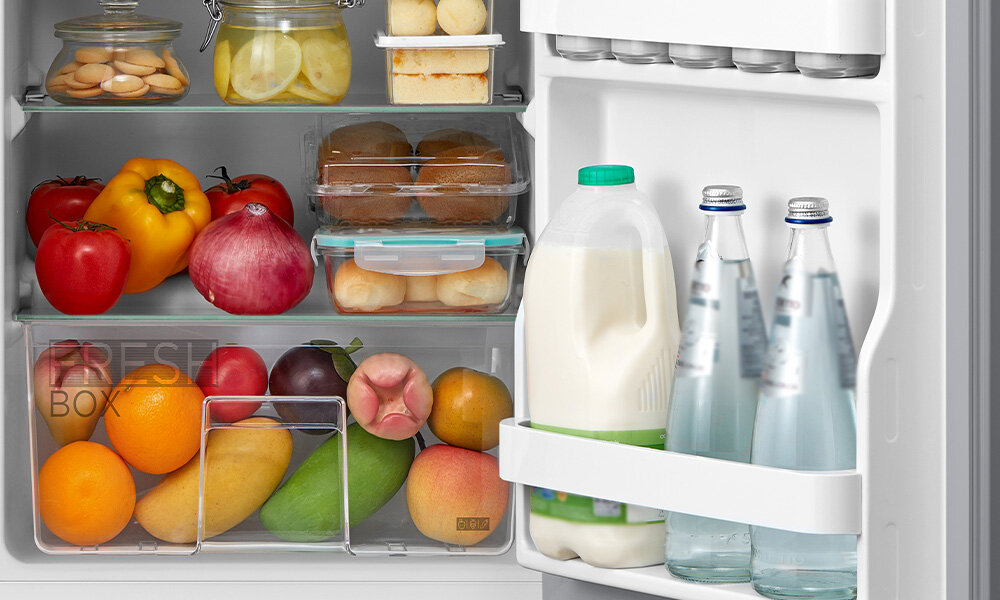 LODÓWKA MIDEA MDRD142FGE50 Zdjęcie pokazuje wnętrze lodówki wypełnione świeżymi owocami, warzywami, nabiałem oraz napojami ustawionymi na drzwiach. Produkty są uporządkowane na szklanych półkach i w dolnej szufladzie, tworząc kolorową i schludną kompozycję szklane półki pojemnik warzywa balkoniki drzwi organizacja lodówki