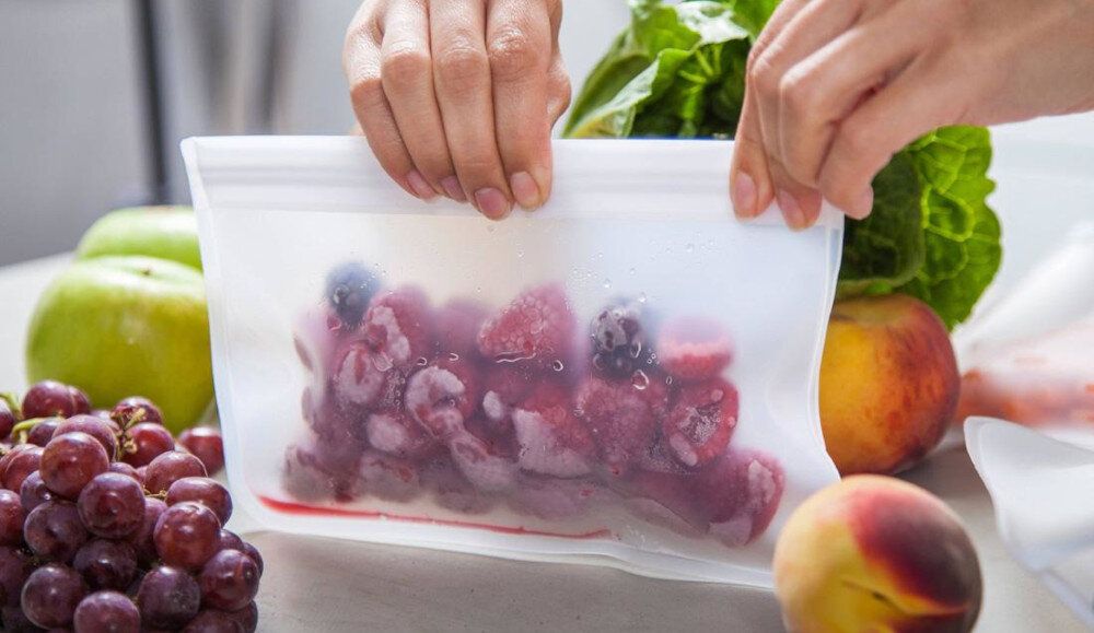 LODÓWKA SIEMENS KF96RSBEA Zamykany worek z mrożonymi owocami trzymany jest nad blatem kuchennym. Obok leżą świeże owoce przygotowane do przechowywania szybkie zamrażanie superfreeze ochrona żywności stabilna temperatura Supermrożenie