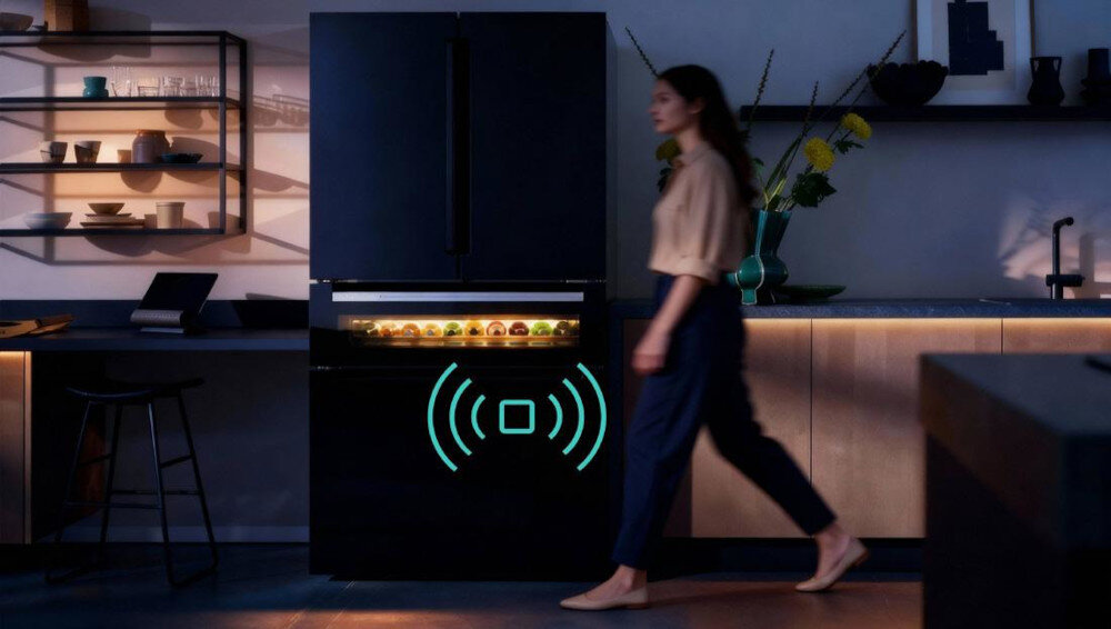 LODÓWKA SIEMENS KF96RSBEA Urządzenie Siemens stoi w kuchni, a osoba przechodzi obok zamrażarki typu dolnego. Grafika fal radiowych sugeruje funkcję otwierania bez uchwytu czujnik ruchu automatyczne oświetlenie smart funkcje podświetlenie panel sterowania