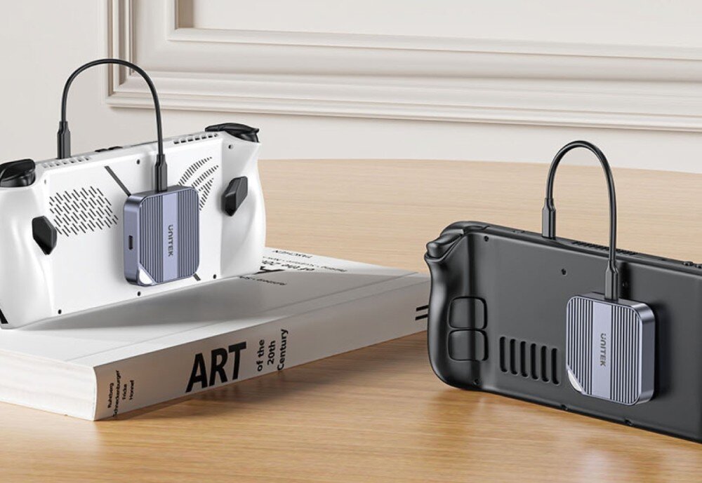 Obudowa dysku UNITEK S1244AGY01 Dwie przenośne konsole do gier, biała i czarna, leżące na stole. Do tyłu każdej z nich przytwierdzony jest dysk Unitek podłączony kablem do górnego portu urządzenia