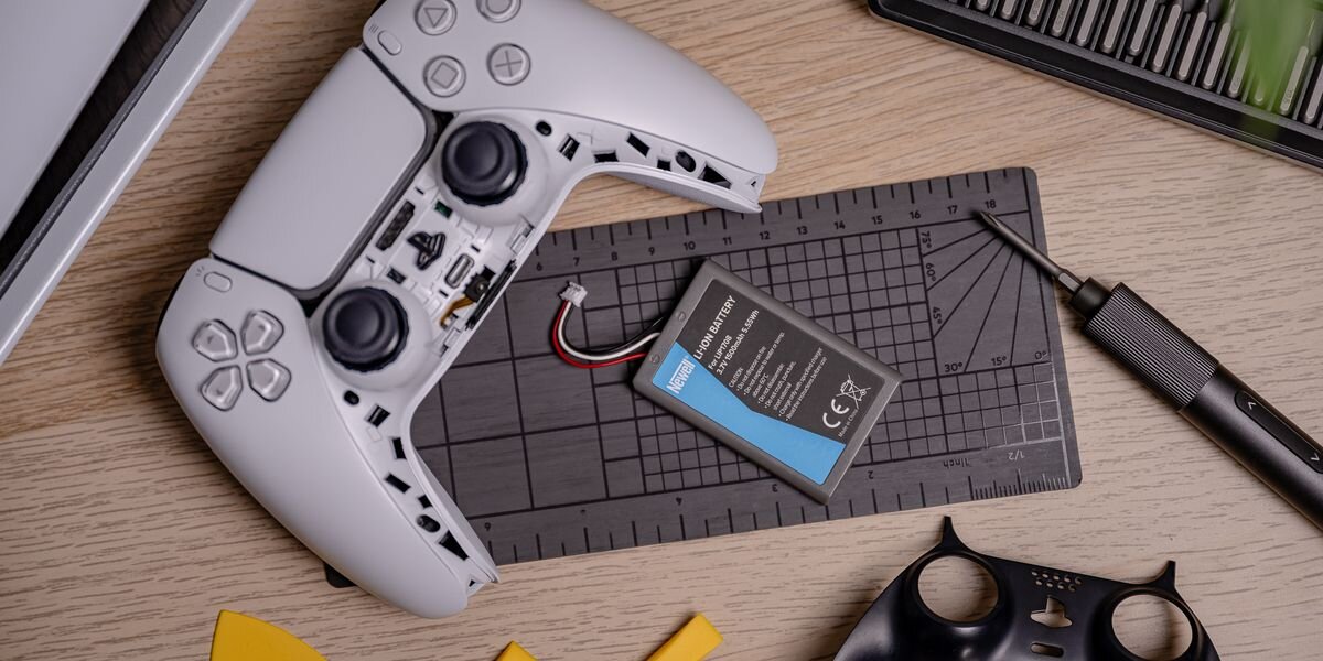 Akumulator NEWELL 1500 mAh LIP1708 do kontrolera DualSense Sony PlayStation 5, Otwarta obudowa białego kontrolera do gier leżąca obok nowej baterii Newell i śrubokręta na macie serwisowej, gra, pad, zasilanie, bateria