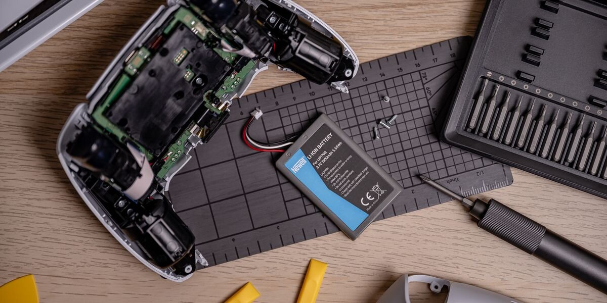 Akumulator NEWELL 1500 mAh LIP1708 do kontrolera DualSense Sony PlayStation 5, Wnętrze białego pada obok szarej baterii Newell, kilku małych śrubek i profesjonalnego zestawu wkrętaków, dokładne, bezadapterowy, lekki, ergonomia