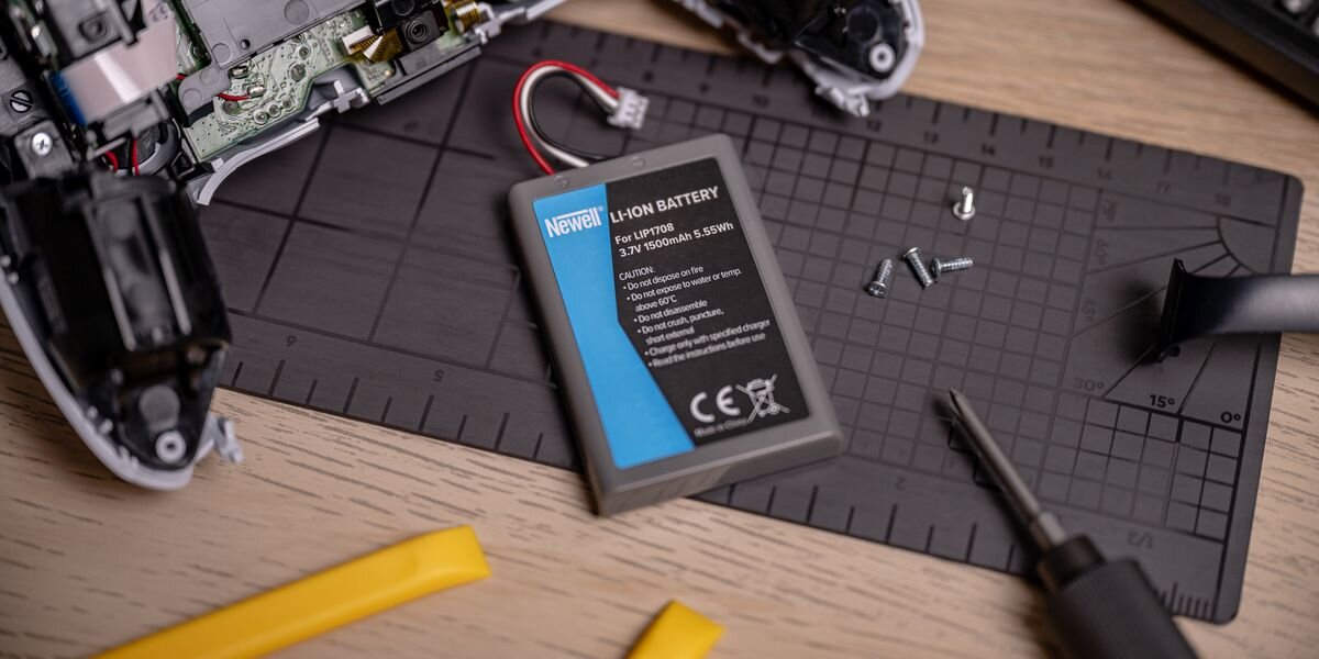 Akumulator NEWELL 1500 mAh LIP1708 do kontrolera DualSense Sony PlayStation 5, Zbliżenie na baterię Newell LIP1708 leżącą na macie magnetycznej obok śrubek i rozmontowanego kontrolera, przeładowanie, przegrzanie, zwarcie, IC