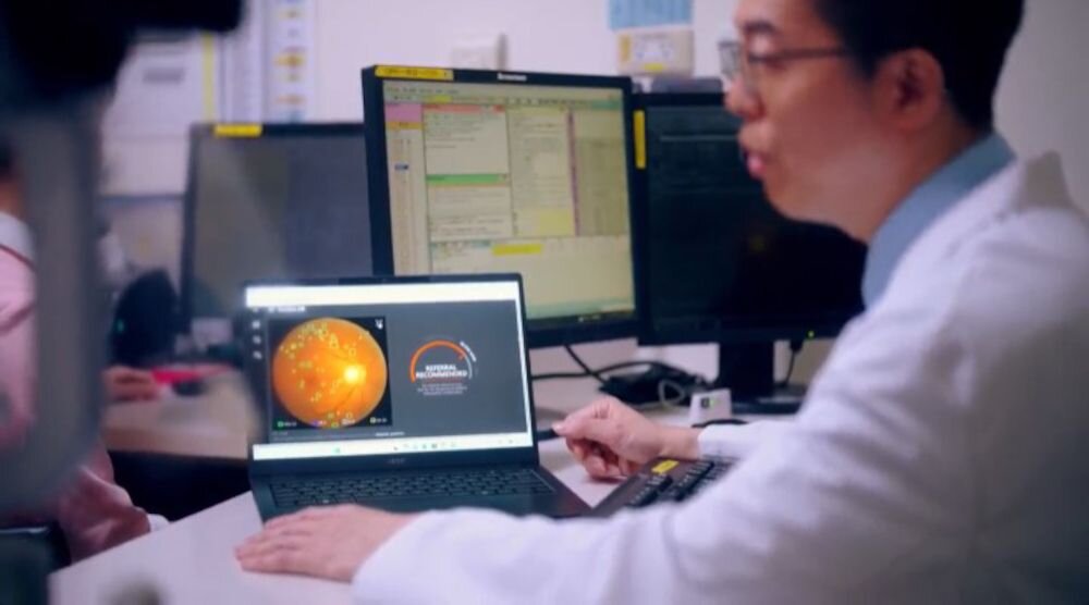 Mężczyzna w białej koszuli pracujący na laptopie Acer TravelMate z pomarańczową sferą i wskaźnikami systemu monitoringu na ekranie w biurze z monitorami w tle i żółtymi karteczkami - Intel Core Ultra, Pamięć RAM LPDDR5X Dysk SSD 