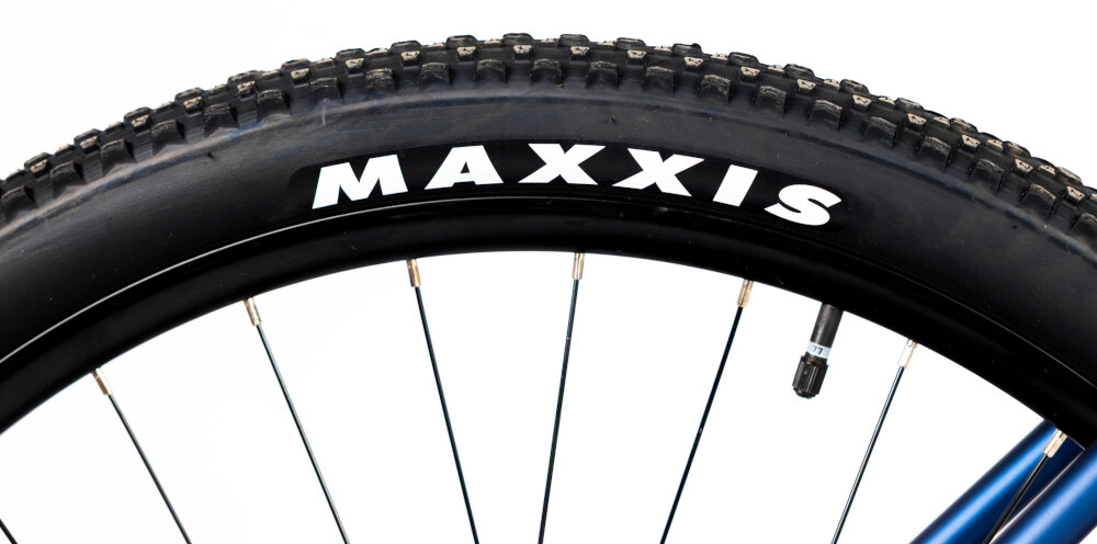 Rower górski MTB INDIANA X-Pulser 3.9 M21 29 cali męski Granatowo-srebrny zbliżenie na oponę rozmiar koła 29 cali łatwe pokonywanie przeszkód duży kontakt koła z podłożem szerokie opony marki MAXXIS dobra przyczepność dwukomorowe wzmocnione obręcze zachowanie regularnego kształtu kół stabilne trzymanie opony bezpieczna i komfortowa jazda regularne sprawdzanie ciśnienia powietrza wartość na bocznej części opony