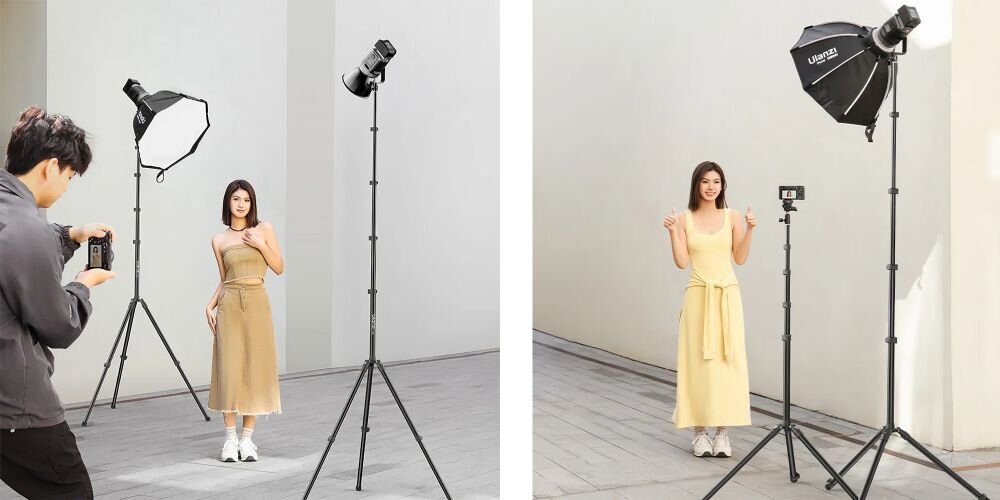 Statyw oświetleniowy z lampą i softboxem podczas sesji zdjęciowej, modelka pozuje, fotograf trzyma aparat, jasne tło