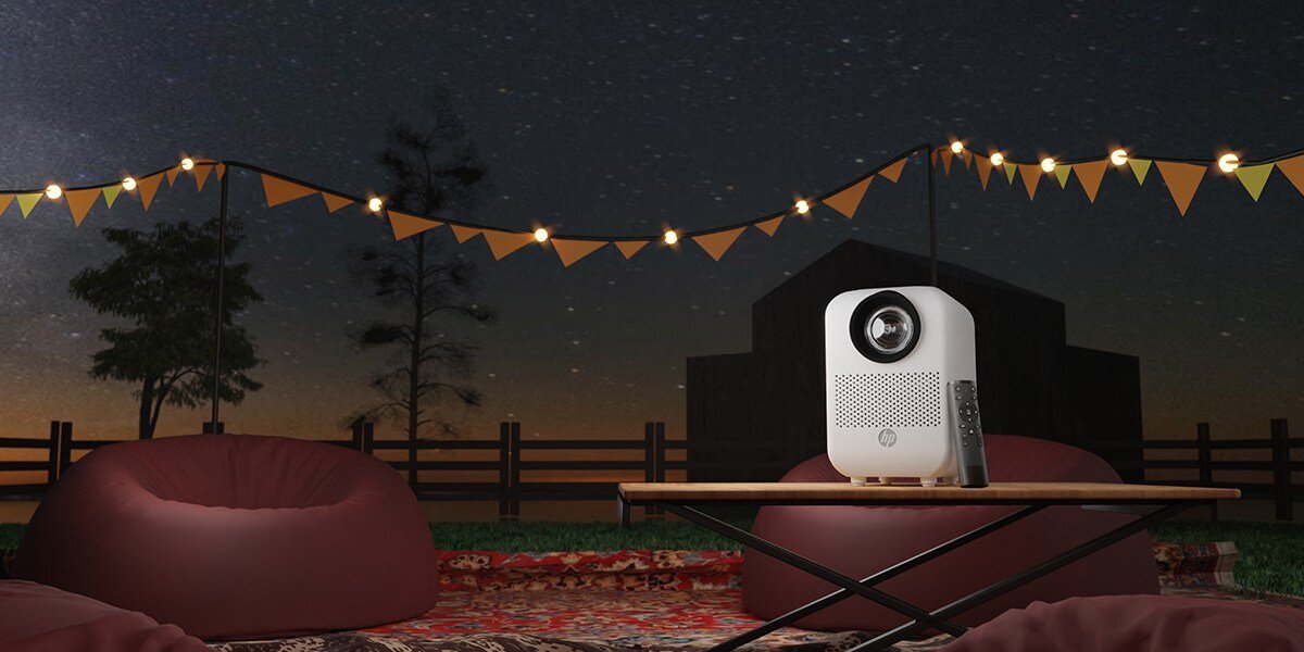 Projektor HP CC180W - Obraz z dowolnego miejsca, projektor z pilotem stojący na stole na świeżym powietrzu
