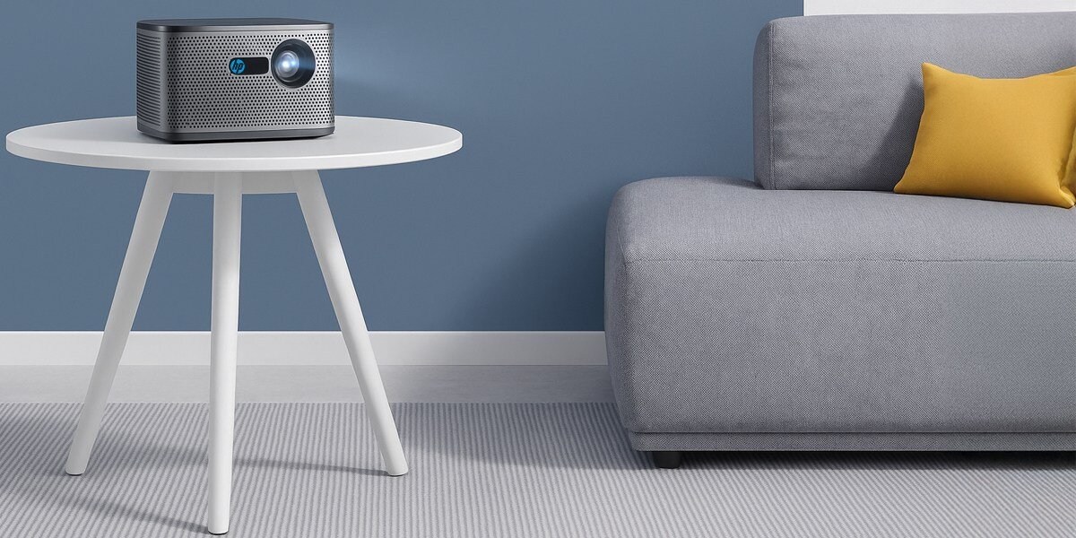 Projektor HP MP2000 Pro - Dźwięk, który robi różnicę, Dwa wbudowane głośniki o łącznej mocy 10 W, praca projektora - 28 dB, projektor stojący na stoliku obok sofy