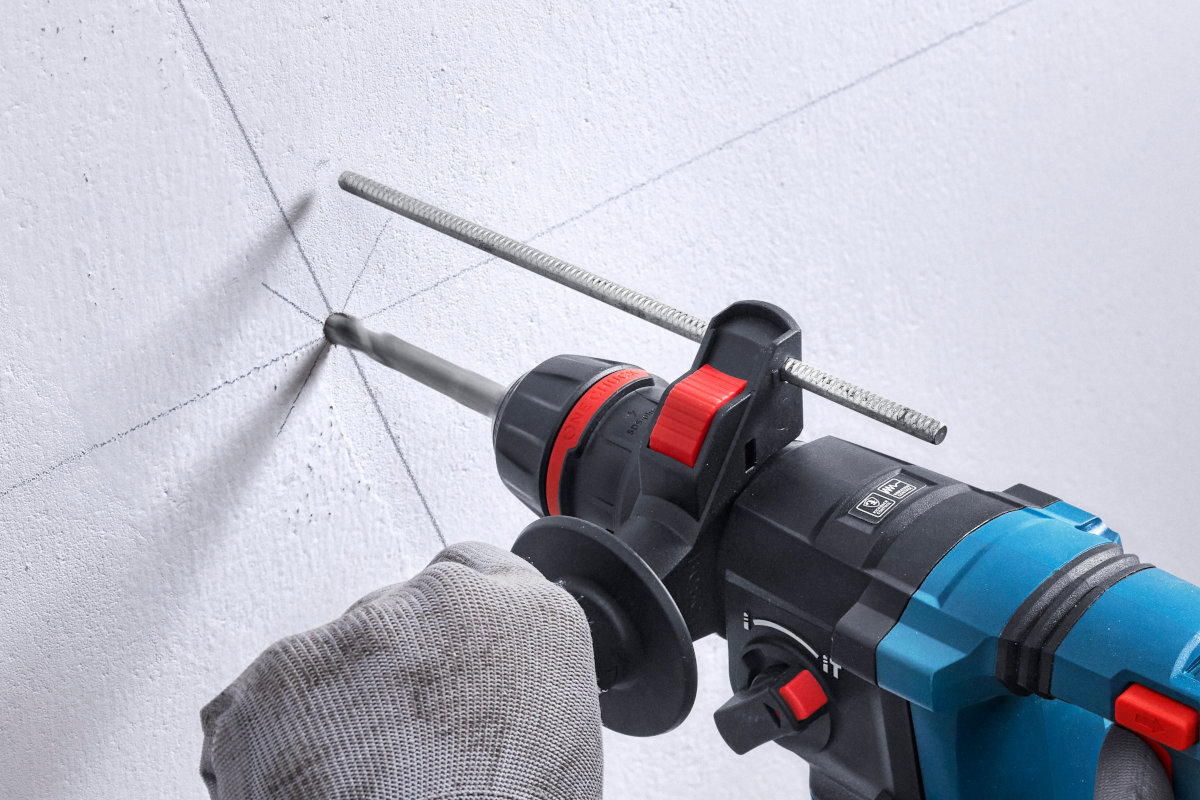 BOSCH Professional GBH 18V-18 X 0611927102 Regulowany ogranicznik głębokości głębokość wiercenia i dłutowania porównaniu z młotami bez ogranicznika - Urządzenie z zamontowanym ogranicznikiem głębokości podczas wiercenia otworu w ścianie.