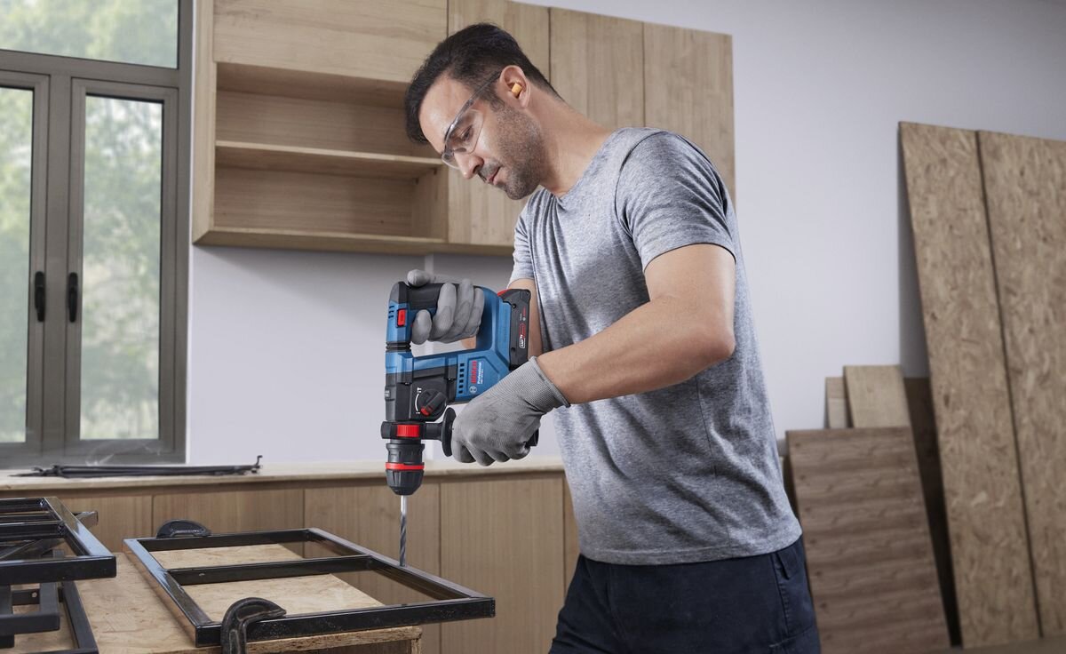 BOSCH Professional GBH 18V-18 X 0611927101 bezszczotkowy silnik stałą moc młotami ze standardowym silnikiem - Mężczyzna wierci otwór w metalowej ramie przy użyciu akumulatorowego młota udarowo-obrotowego.