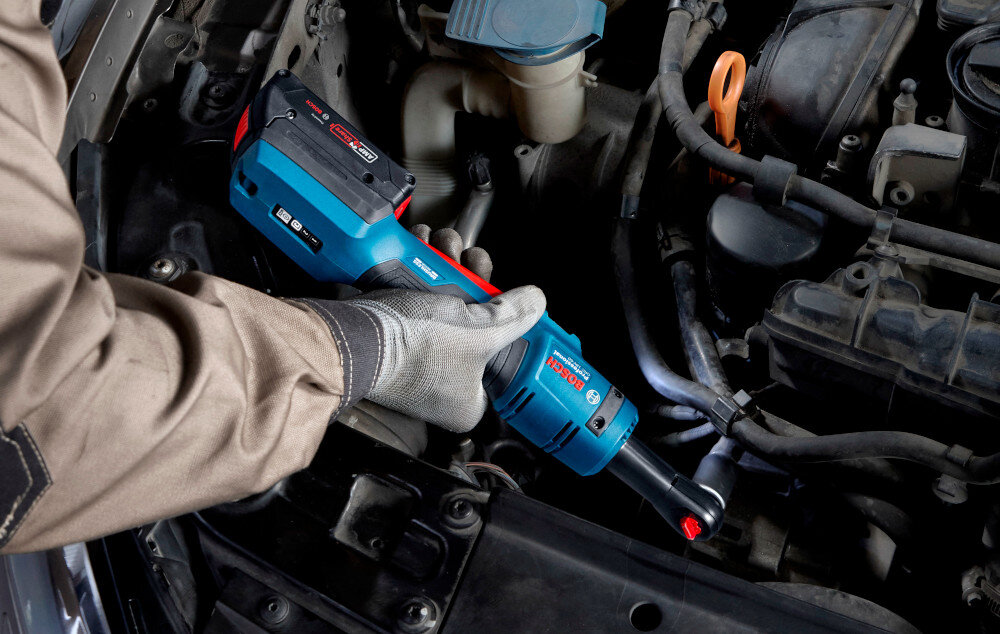 Klucz akumulatorowy grzechotka BOSCH GRC 18V-60 06019N8001 silnik samochodowy osoba dokręca śrubę w instalacji ułatwia dokręcanie i odkręcanie śrub w serwisie samochodowym przy montażu konstrukcji stalowych ergonomiczny kształt intuicyjne tryby pracy