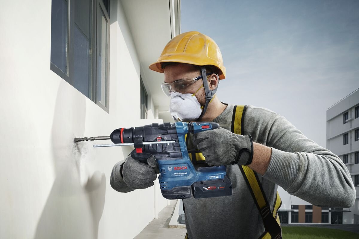 BOSCH GBH 18V-22 X - Mężczyzna używa akumulatorowego młota udarowo-obrotowego do wiercenia w ścianie.