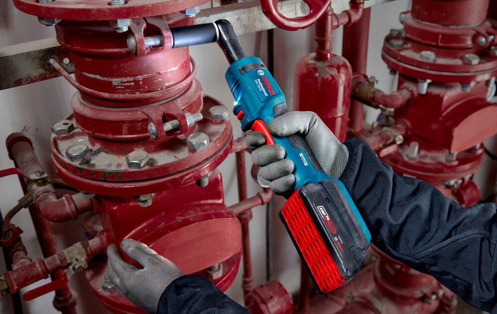 Klucz akumulatorowy grzechotka BOSCH GRC 18V-60 06019N8002 pomieszczenie czerwone rury osoba przykręca śrubę do rury waga około 0,9 kg bez akumulatora smukła dobrze wyprofilowana rękojeść pokrycie z antypoślizgowego miękkiego materiału długość korpusu wynosi 363 mm stabilność chwytu ogranicza ślizganie się dłoni