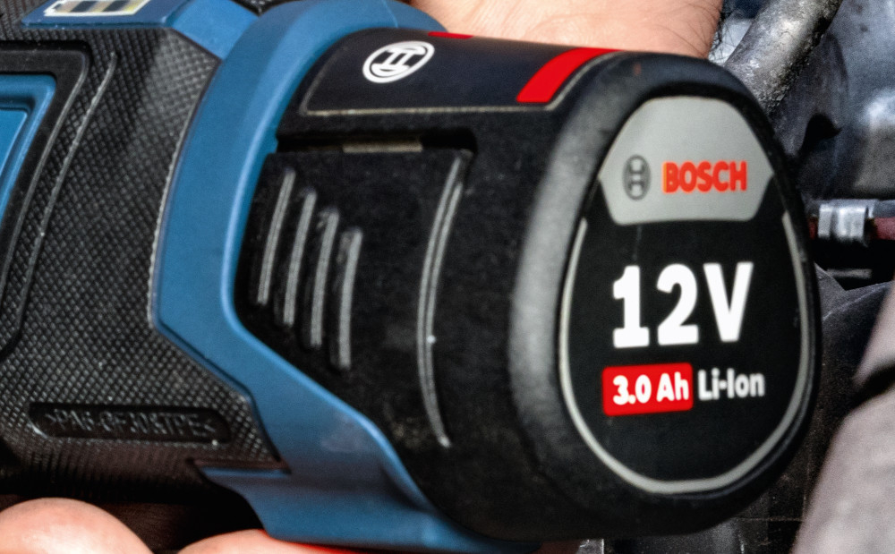 Klucz akumulatorowy grzechotka BOSCH Professional GRC 12V-60 3-8 SN 06019N8301 warsztat silnik osoba dokręca śrubę w silniku zbliżenie na akumulator zasilane akumulatorem akumulator o napięciu 12 V bezpieczeństwo i swoboda manewrowania szybsze tempo realizacji zleceń