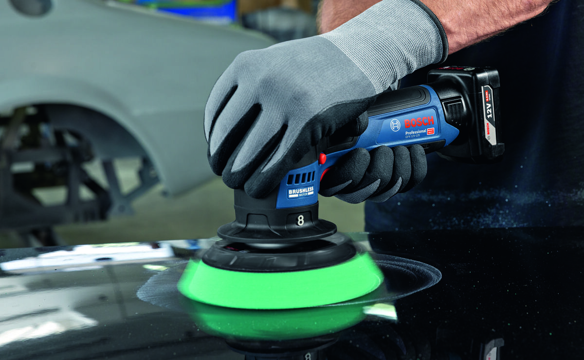 BOSCH Professional GPX 12V- 125 06019L4100 Silnik bezszczotkowy BOSCH Professional GPX 12V- 125 06019L4100 mniejszym zużyciem elementów standardowy silnik szczotkowy - Zbliżenie na dłonie w rękawicach ochronnych trzymające polerkę akumulatorową Bosch podczas pracy na powierzchni lakierowanej.