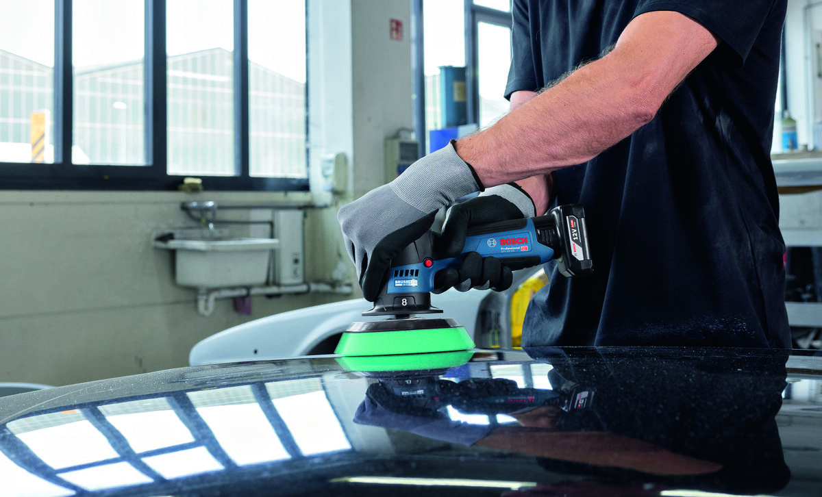 BOSCH Professional GPX 12V- 125 06019L4100 Blokada włącznika polerowanie ciągłe Wygodna konstrukcja 1,5 kg - Mężczyzna w rękawicach ochronnych poleruje maskę samochodu za pomocą polerki akumulatorowej Bosch.