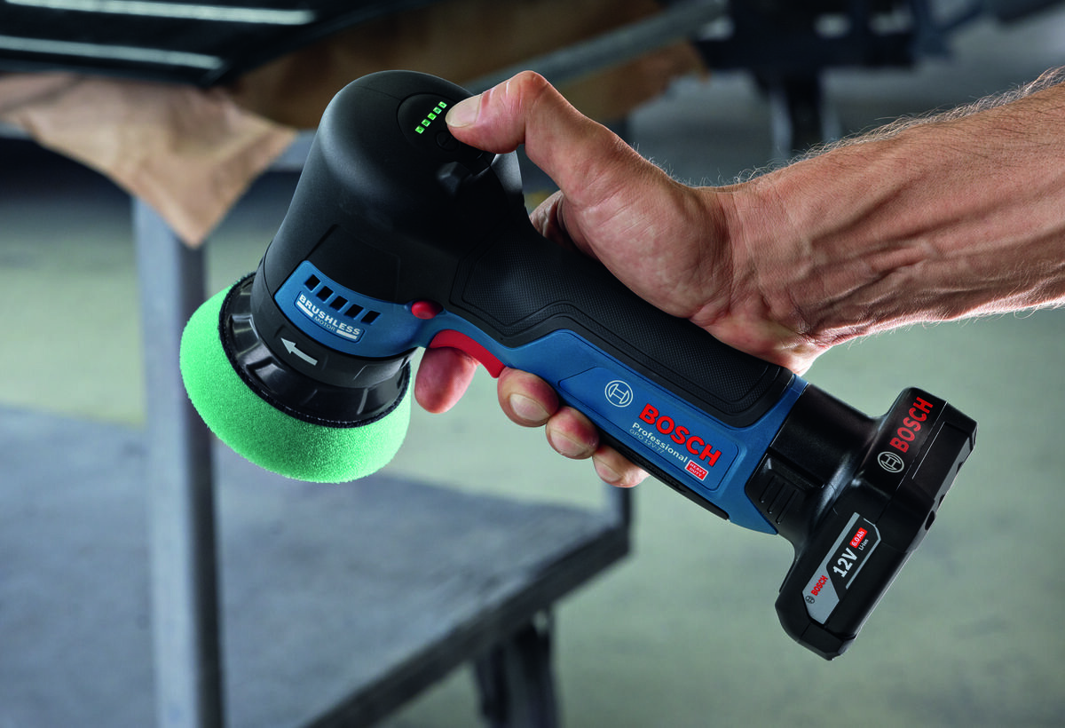 BOSCH Professional GPO 12V-77 06019L3000 Interfejs HMI poziom naładowania akumulatora umożliwia wybór jednego z 5 ustawień prędkości stan zasilania dopasować parametry - Mężczyzna trzyma polerkę akumulatorową Bosch i sprawdza stan naładowania baterii przyciskiem na obudowie.