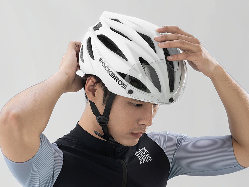 Kask rowerowy ROCKBROS 8386824304060 Biały Szosowy (rozmiar 58-62), regulacja, dopasowanie, ce, ochrona, Mężczyzna obiema dłońmi zakłada kask na głowę.