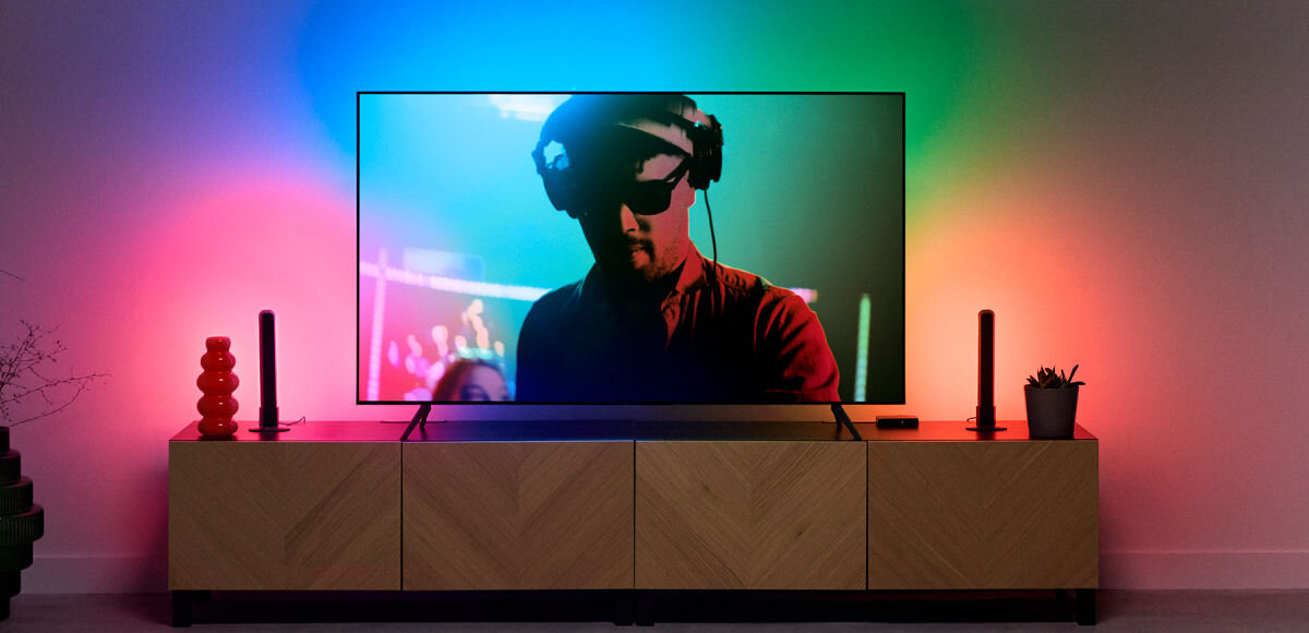 Lampa WIZ Bar 929004732301 Wi-Fi , Lampa, która maluje światło, Telewizor na szafce a w otoczeniu jego włączona lampa podłogowa gradient