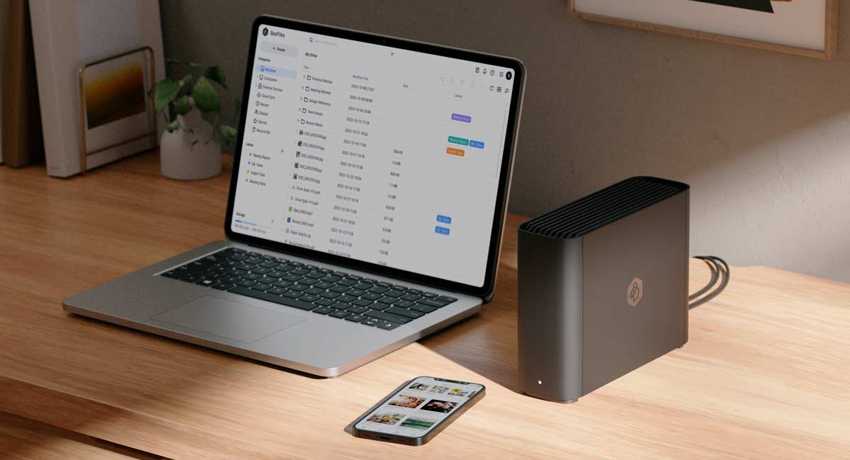 Synology BeeStation Plus BST170-8T obok telefonu i laptopa na drewnianym biurku.