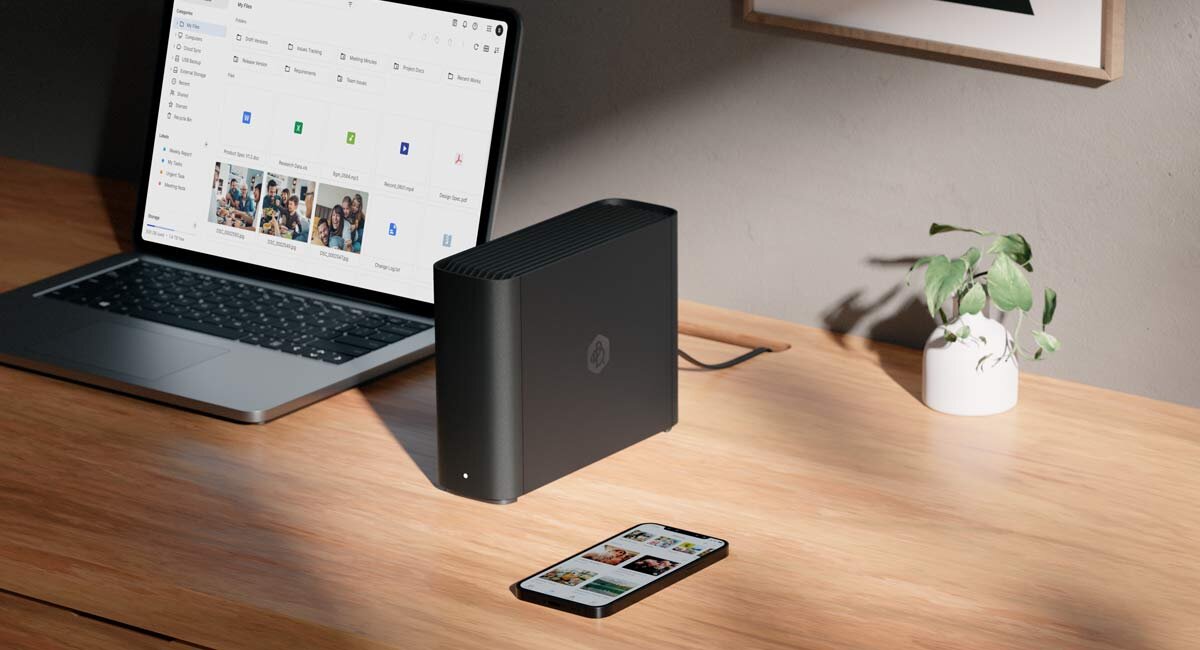 Synology BeeStation Plus BST170-8T na drewnianym biurku obok telefonu i laptopa.