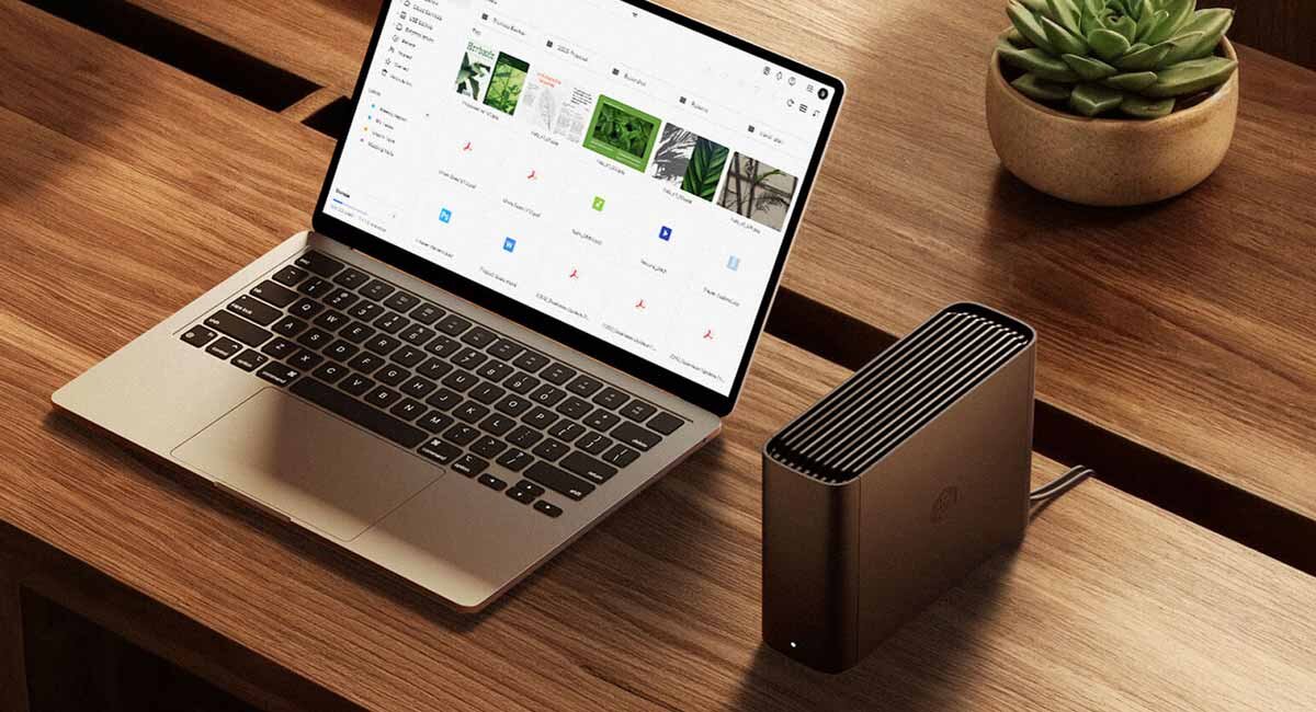 Synology BeeStation Plus BST170-8T na drewnianym biurku przy laptopie.