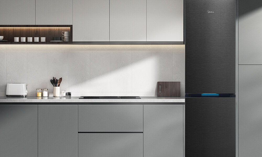 LODÓWKA MIDEA MDRB548MIC45P Lodówka stoi przy kuchennej zabudowie w prostym, jasnym wnętrzu. Całość jest schludna, z widocznymi drobnymi akcesoriami kuchennymi na blacie
