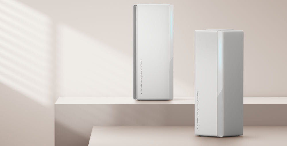 Router XIAOMI Mesh System AX3000 NE 2.4 / 5 GHz (DualBand), Wi-Fi Mesh (3 szt.) prezentacja dwóch routerów stojących na beżowym dwustopniowym podeście beżowe tło wpadająca poświata światła dziennego technologia sieci kratowej Mesh eliminacja martwych stref