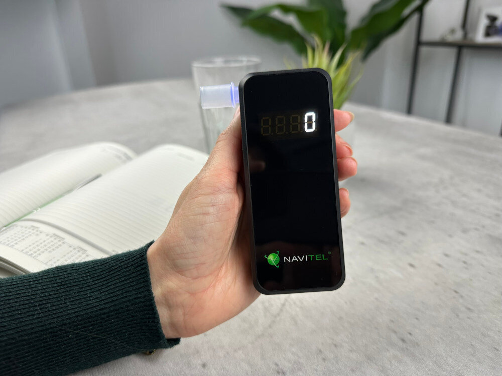 NAVITEL ALC05 - Alkomat trzymany w dłoni nad otwartym kalendarzem na biurku