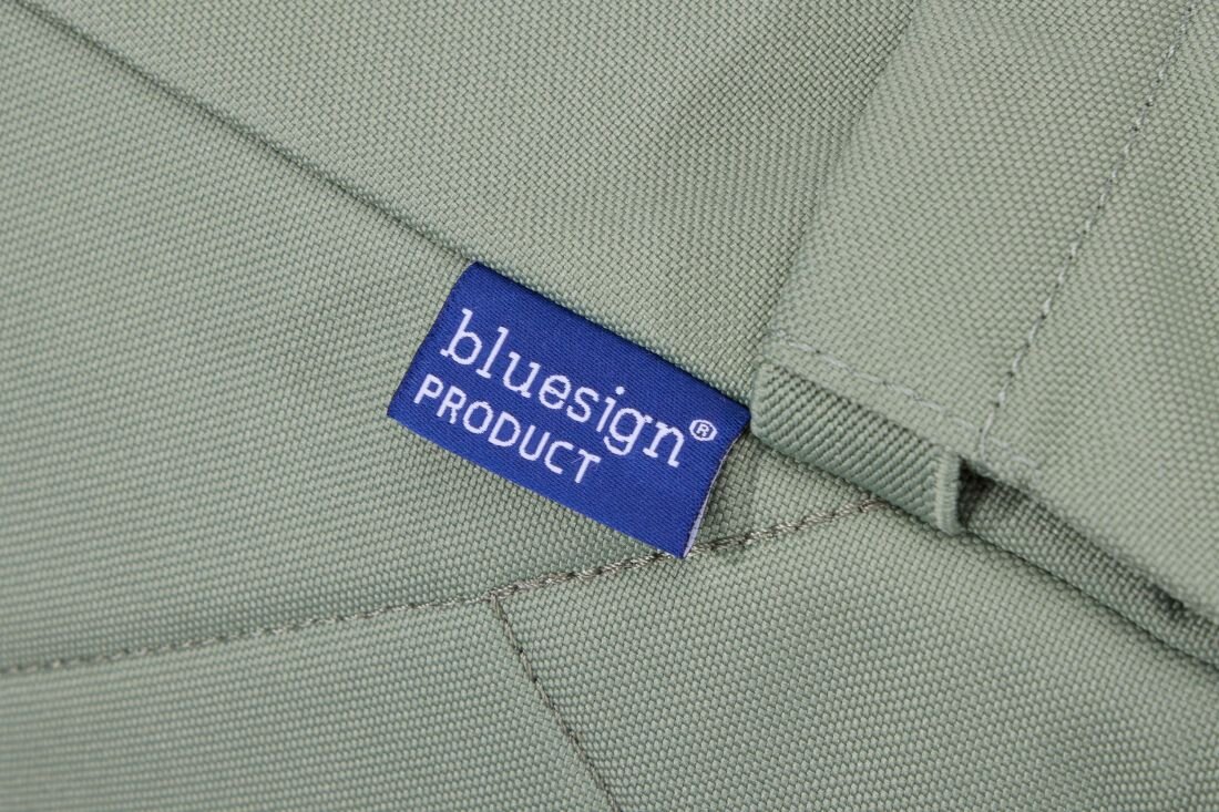 Jasnozielony materiał z naszywką w kolorze niebieskim z białym napisem \'bluesign PRODUCT\'.