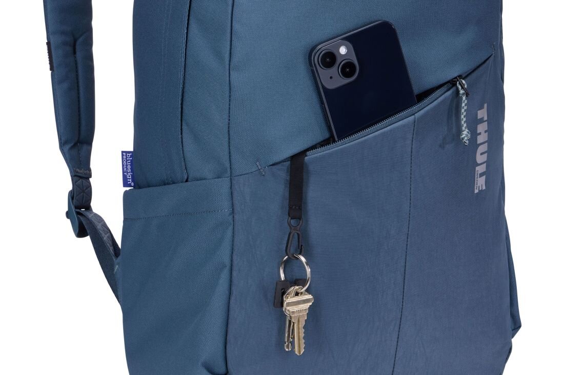 Ciemnoniebieski plecak z widoczną kieszenią, w której znajduje się telefon i przypięte klucze. Na plecaku widoczne jest logo \'THULE\'.