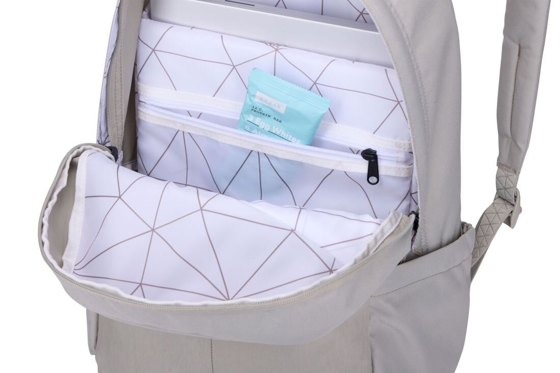 Otwarty plecak w jasnobeżowym kolorze z widoczną kieszenią na laptopa i dodatkową kieszenią zamykaną na zamek. W środku znajduje się opakowanie z napisem \'SOAP WHITE\'.