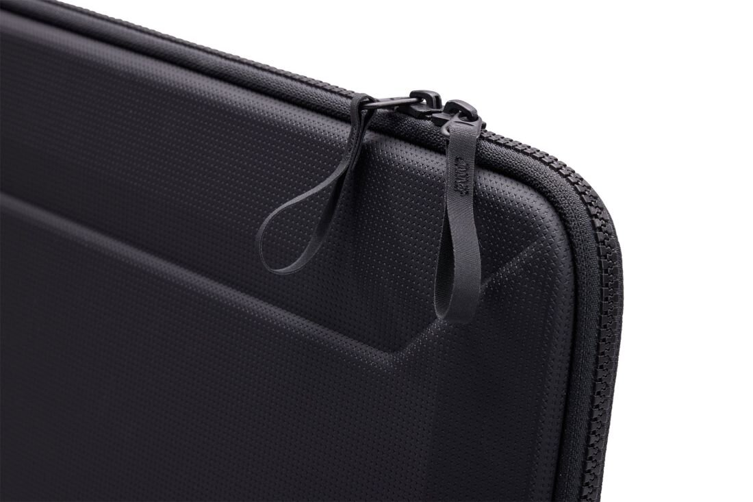Etui Thule Gauntlet Sleeve prezentuje sztywną konstrukcję i podwójny zamek błyskawiczny na jasnym tle podczas transportu laptopa 