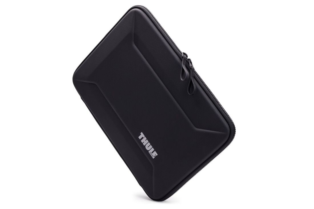 Etui Thule Gauntlet Sleeve prezentuje sztywną obudowę z podwójnym zamkiem błyskawicznym na jasnym tle podczas transportu laptopa  