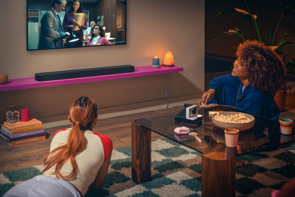 Soundbar JBL BAR 300 MkII 5.0-kanałowy system audio moc 450 W bez subwoofera, soundbar stojący na blacie pod zwieszonym telewizorem, osoby oglądające film