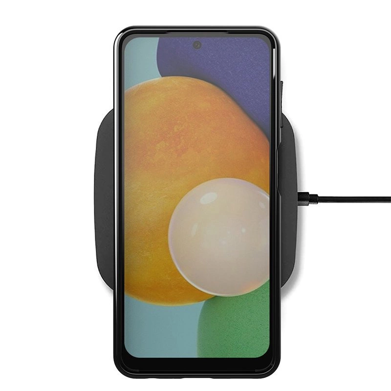 Na obrazie widoczny jest smartfon w czarnym etui, umieszczony na ładowarce bezprzewodowej. Ekran telefonu wyświetla kolorową grafikę z okrągłymi kształtami.