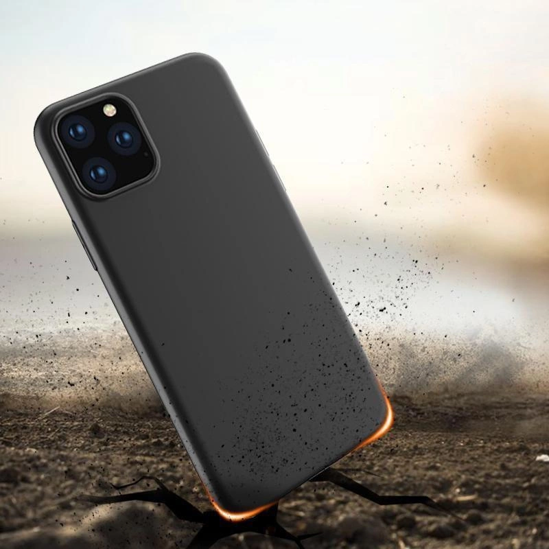 Czarne etui na telefon leży na ziemi, wokół unosi się pył. Etui ma wycięcia na aparat z trzema obiektywami i lampą błyskową.