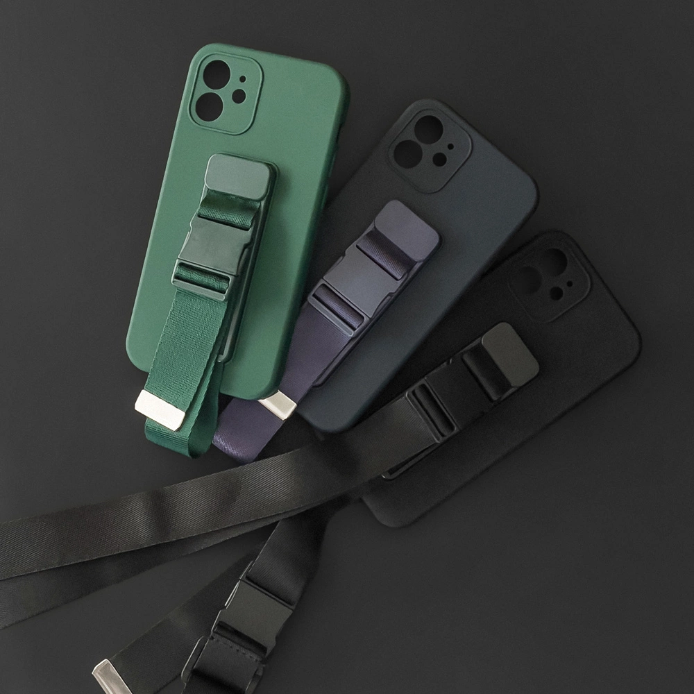 Na obrazie widoczne są cztery silikonowe etui na telefon w kolorach zielonym, granatowym, czarnym i ciemnoszarym, każde z przypiętą smyczą. Etui mają wycięcia na aparat i przyciski oraz metalowe klamry na smyczach.